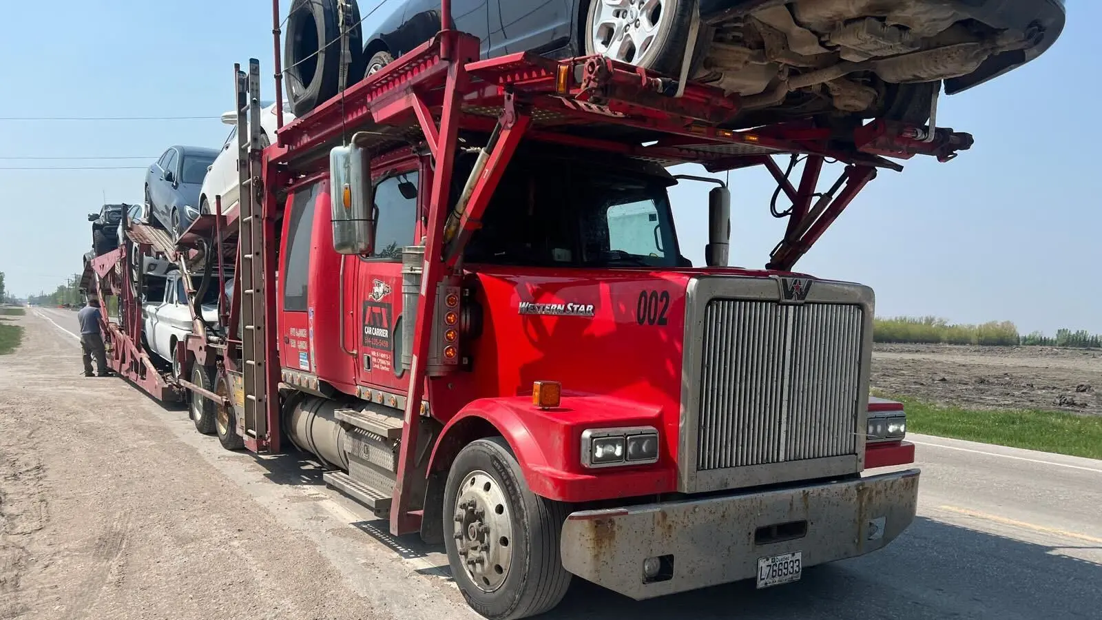 Auto carrier truck with cars driving across Canada