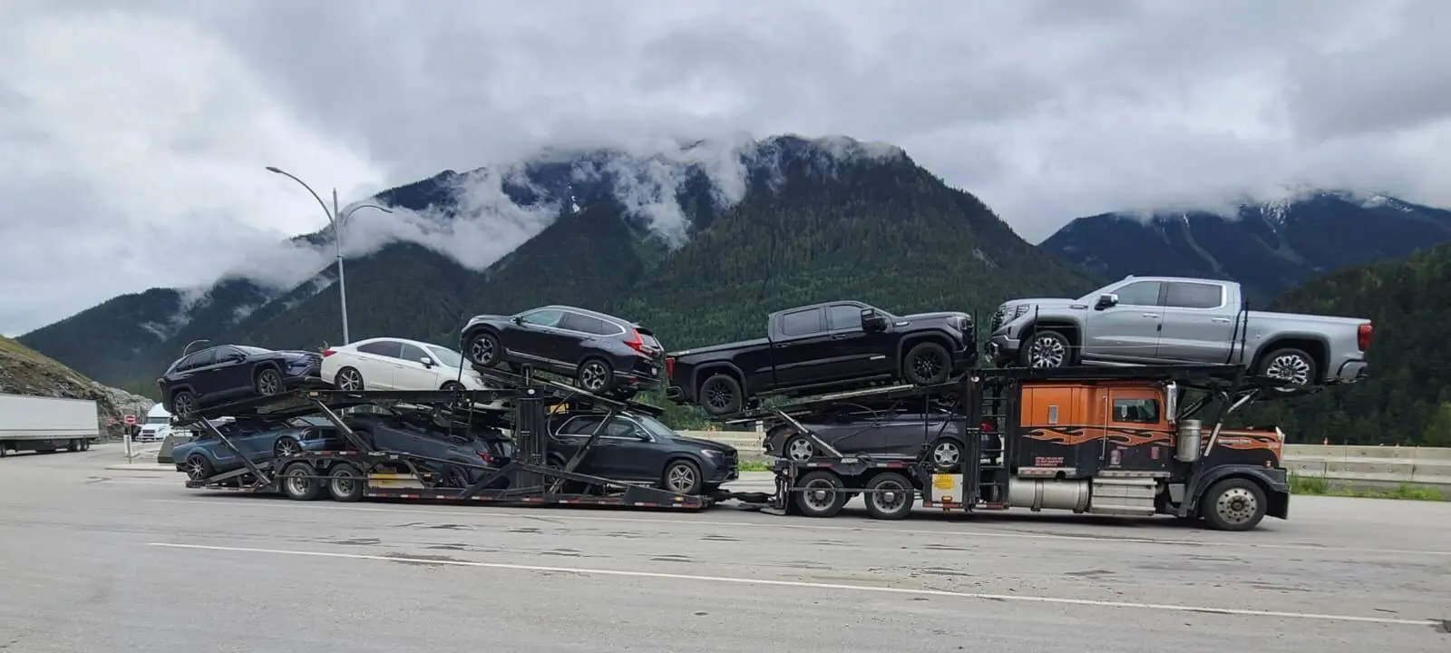 Vehicle transport truck driving through forested highway in British Columbia