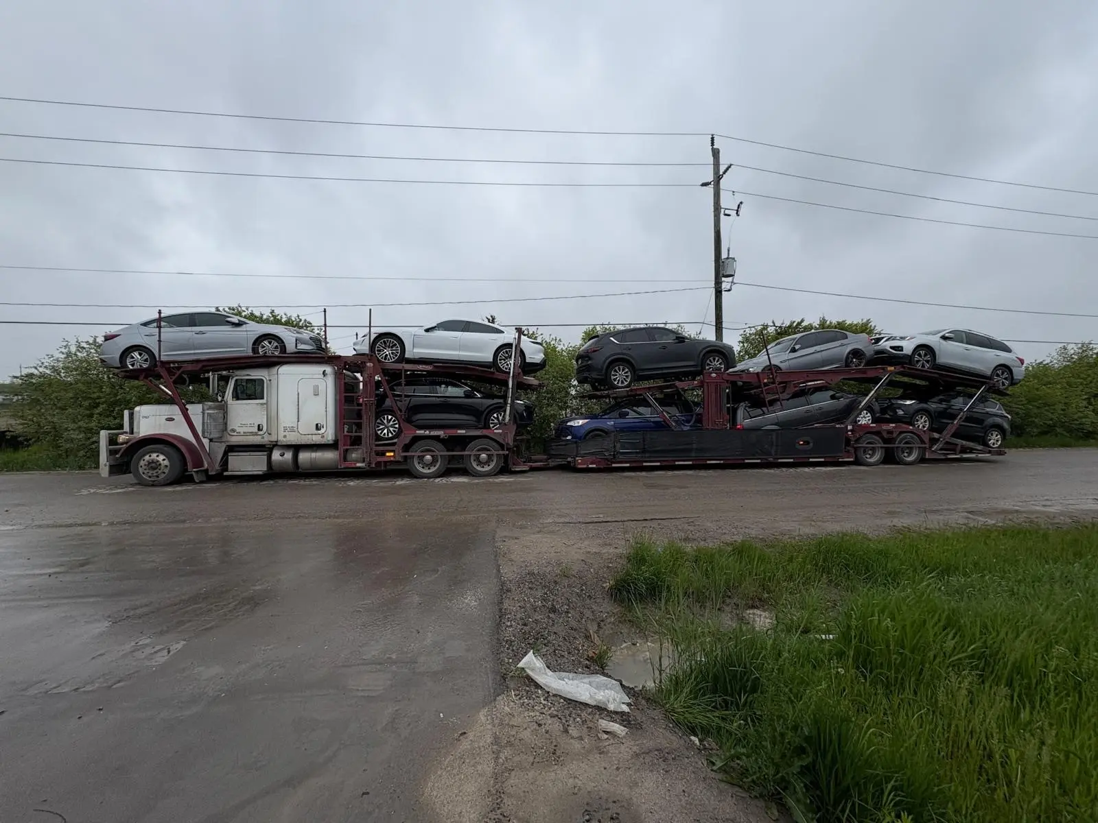 Car carrier driving through Ontario highway with Toronto skyline in background